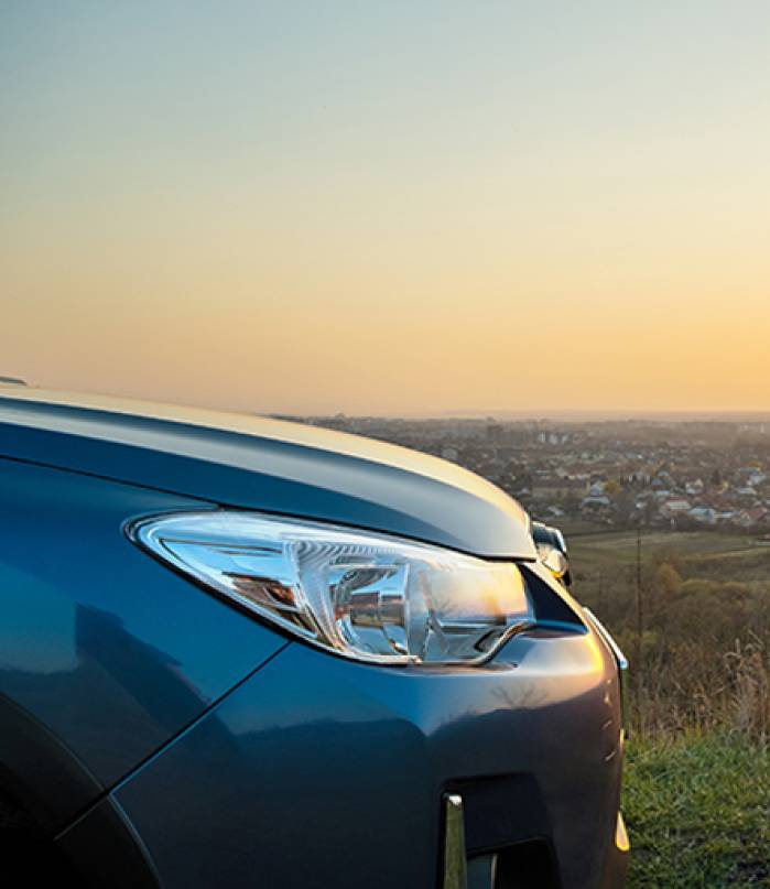 Close up detail of front headlight lamp of modern car at sunset.